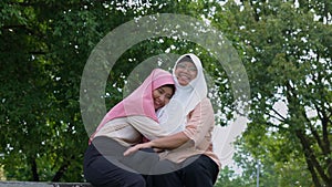 Muslim careful caregiver or nurse taking care of the patient in the hospital park. Happy Muslim mother in hijab hugging daughter.