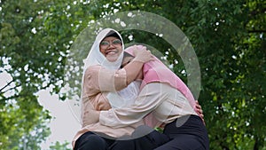 Muslim careful caregiver or nurse taking care of the patient in the hospital park. Happy Muslim mother in hijab hugging daughter.