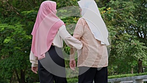 Muslim careful caregiver or nurse taking care of the patient in the hospital park. Happy Muslim mother in hijab hugging daughter.