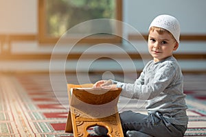 The Muslim child prays in the mosque, the little boy prays to God, Peace and love in the holy month of Ramadan.