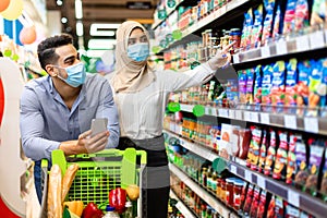 Muslim Couple Choosing Food In Supermarket Doing Grocery Shopping Together