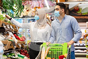 Muslim Couple Doing Grocery Shopping Wearing Face Masks In Supermarket