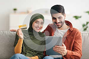 Muslim Couple Doing Online Shopping Via Digital Tablet At Home