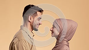 Muslim Couple In Love Smiling One Another Over Beige Background