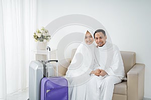 Muslim couple sit wearing white traditional clothes before umrah