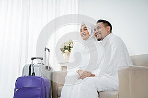 Muslim couple sit wearing white traditional clothes before umrah