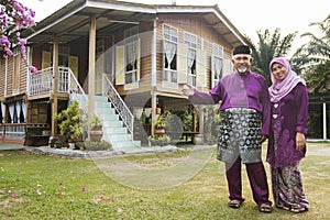 Muslim couple standing outside their house