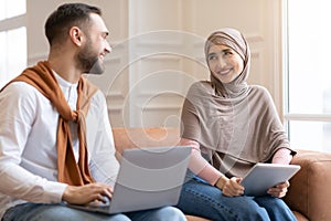 Muslim Couple Using Computers Laptop And Digital Tablet At Home