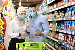 Muslim Couple Using Smartphone Scanning Product During Shopping In Supermarket
