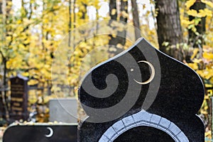 Muslim crescent moon with a star on a dark marble gravestone. Waxing moon Islamic symbol on Muslim graveyard