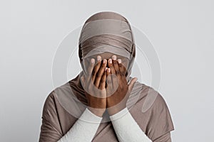 Muslim Discrimination. Scared black islamic woman in hijab covering face with hands