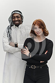 Muslim entrepreneur and a contemporary red-haired girl strike a pose together against a clean white background