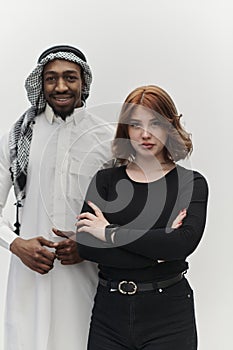 Muslim entrepreneur and a contemporary red-haired girl strike a pose together against a clean white background