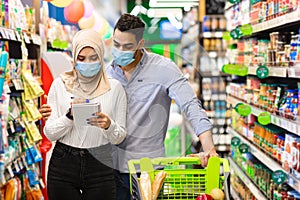 Muslim Family Doing Grocery Shopping In Supermarket, Wearing Face Masks
