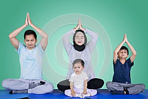 Muslim family doing yoga exercise on studio