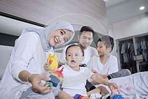 Muslim family enjoying leisure time on the bed