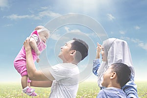 Muslim family playing with baby on meadow