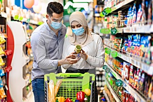 Muslim Family Shopping Groceries In Supermarket, Wearing Face Masks