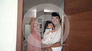 muslim family standing in front of their front door house welcoming guest