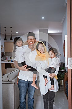 muslim family standing in front of their front door house welcoming guest at home