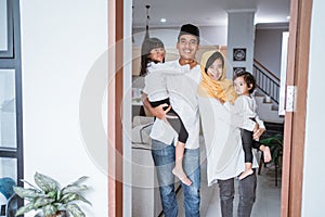 muslim family standing in front of their front door house welcoming guest at home