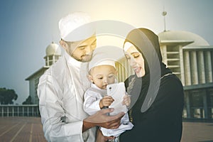 Muslim family use cellphone with mosque background