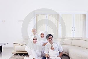 Muslim family watching tv together in living room