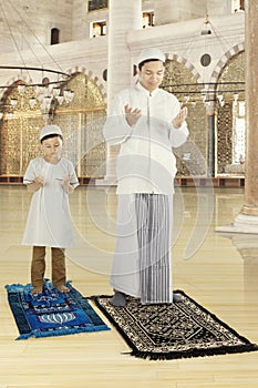 Muslim father praying with his son