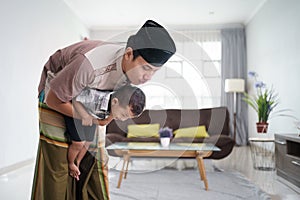 muslim father praying at home while babysit his son photo