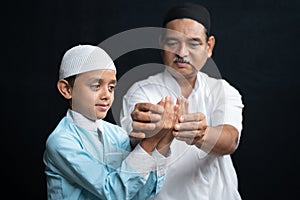 Muslim Father teaching his son how to do Salah or payer in a Islamic way.