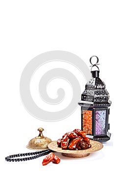 The Muslim feast of the holy month of Ramadan Kareem. Beautiful background with a shining lantern Fanus and dried dates on white.