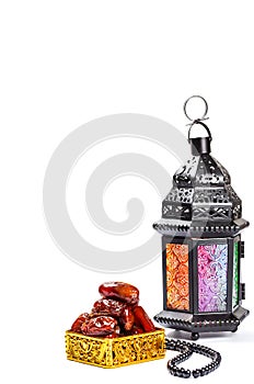 The Muslim feast of the holy month of Ramadan Kareem. Beautiful background with a shining lantern Fanus and dried dates on white.