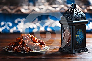 The Muslim feast of the holy month of Ramadan Kareem. Beautiful background with a shining lantern Fanus and dried dates on wooden
