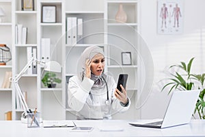 Muslim female doctor experiencing stress while on the phone