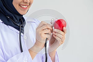 Muslim Female doctor  with  the stethoscope holding heart white background in hospital, Concept: taking care of the family