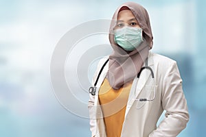 Muslim female doctor wearing hijab and suit, standing with protective face mask , ready to fight coronavirus global pandemic