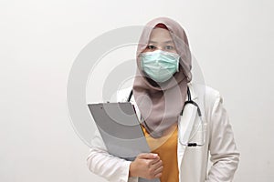 Muslim female doctor wearing hijab and suit, standing with protective face mask , ready to fight coronavirus global pandemic