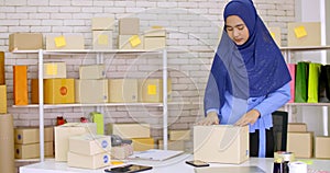 Muslim female merchandiser preparing parcel at the office