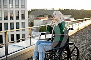 Muslim female with mobility issues daydreaming on terrace