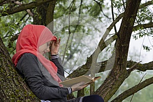 Muslim female student reading a book in nature, outdoor