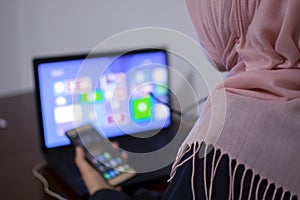 Muslim female student using laptop and mobile phone