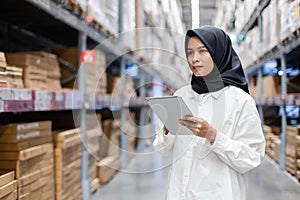 Muslim female wearing hijab warehouse worker holding tablet checks stock on shelf storehouse. businesswoman islamic entrepreneurs