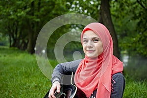 Muslim girl with blue eyes playing acoustic guitar