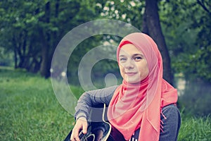 Muslim girl with blue eyes playing acoustic guitar