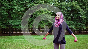 Muslim girl exercising with dumbbells outdoor