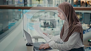 Muslim girl in hijab student freelancer businesswoman woman working on laptop at business mall check documents enter