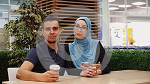 Muslim girl and young man posing looking at camera, embrace