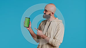 Muslim guy holding smartphone with greenscreen display