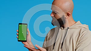Muslim guy holding smartphone with greenscreen display