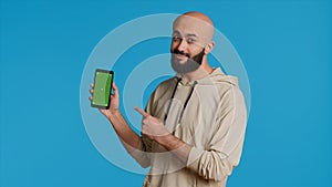 Muslim guy holding smartphone with greenscreen display